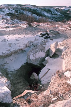 Medicine Hole in winter. This photograph was taken in 1985. In more recent years the rocks that were placed over part of the entrance to discourage cavers have been removed. Spelunker Jerry Forney noted while exploring Medicine Hole that there was a pile of pebbles on the floor of the cave below the opening which had formed from people over the years dropping pebbles to test the depth of the 70 foot-deep crack. 